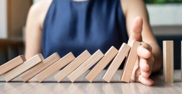 Businesswoman hand Stopping Falling wooden Dominoes