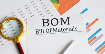 BOM - Bill Of Materials text with magnifying glass lens on the office desk table.